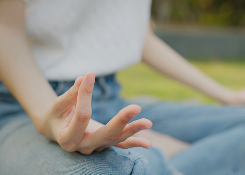 Stressmanagement: Frau sitzt im Grünen im Lotussitz